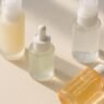 A flatlay of Korean beauty skincare products including essence, serum and sunscreen bottles on a soft background